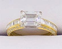 A Diamond single stone set ring with diamond set shoulders and shank sides. Emerald cut diamond