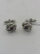 A pair of silver cuff links in the form of knots set with garnets.