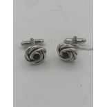 A pair of silver cuff links in the form of knots set with garnets.