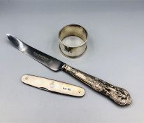 Three hallmarked silver items, a pen knife, napkin ring and a silver handled knife.