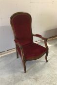 A single low Victorian armchair with red velvet upholstery