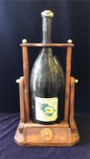 A Jeroboam of Remy Martin cognac on a wooden stand, the bottle is about a quarter full and has a