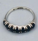 A White gold ring with seven dark (untested) stones.