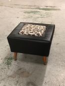 A Mid Century Black footstool with leopard print inset on teak legs with brass feet.