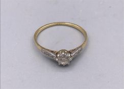 A Diamond ring with diamond shoulders and an 18ct yellow gold setting