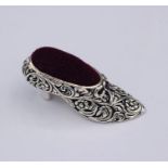 A silver pincushion in the form of a shoe.