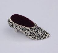 A silver pincushion in the form of a shoe.