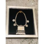 An Arabian silver necklace with silver coins in a box frame.