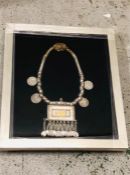 An Arabian silver necklace with silver coins in a box frame.