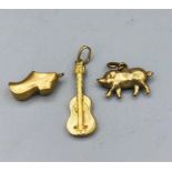Three gold charms, pig, guitar and a shoe.
