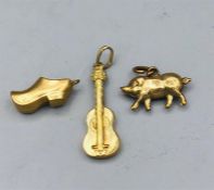 Three gold charms, pig, guitar and a shoe.