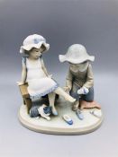 A Lladro figure of a girl trying on shoes
