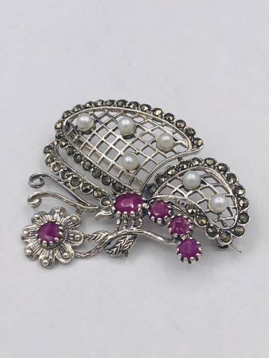 A silver brooch set with rubies and pearls