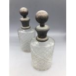 Pair of cut glass bottles with white metal stoppers.