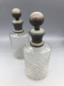 Pair of cut glass bottles with white metal stoppers.