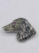 A silver dog brooch set with Marcasite's and ruby eye