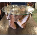 A Teak Tree Trunk Based coffee table with glass top.