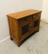 A light oak sideboard with two drawers and carved cupboard doors in an Arts and Crafts style