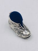 A silver boot shaped pincushion