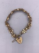 A 9ct yellow gold gate bracelet with heart shaped fastener. (7.7g)