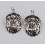 A pair of silver earrings in the form of peacocks