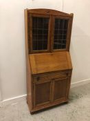 A light Oak Bureau bookcase with upper glazed doors in an Arts and Crafts style.