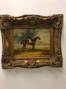 An oil on board of a racehorse and jockey in an ornate frame.