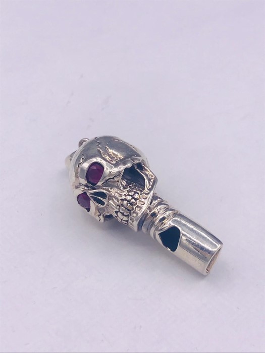 An unusual silver skull shaped whistle with ruby eyes