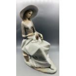 A Large Lladro figure of a lady with a dog on her lap.