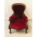 A Mahogany Victorian spoon back armchair with scrolled legs and button back upholstery.