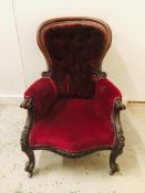 A Mahogany Victorian spoon back armchair with scrolled legs and button back upholstery.