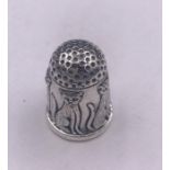 A silver thimble with embossed images of cats