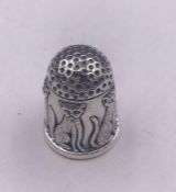 A silver thimble with embossed images of cats