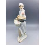 A Lladro figure of a girl carrying a chicken and a basket.