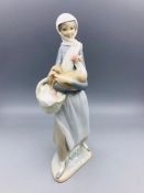 A Lladro figure of a girl carrying a chicken and a basket.