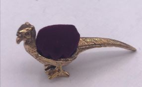 A brass pincushion in the form of a pheasant