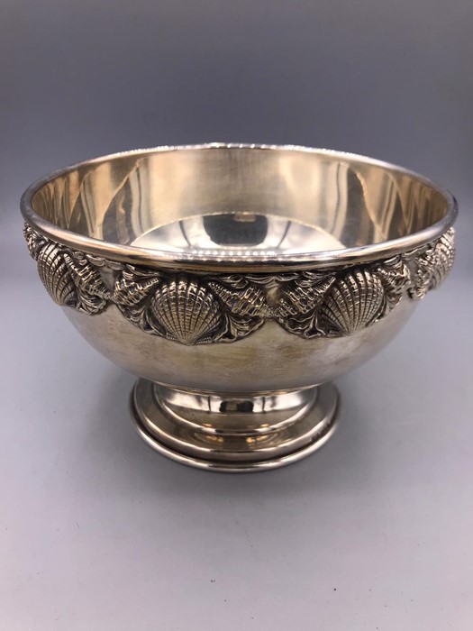 A silver bowl with shell design to the rim.