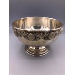 A silver bowl with shell design to the rim.
