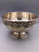 A silver bowl with shell design to the rim.