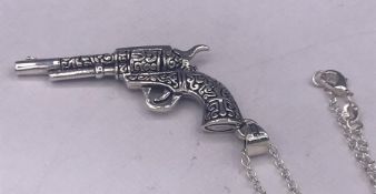 A silver hand gun pendant on a silver chain