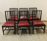 A set of six stick back dining chairs with red vinyl seats.