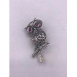 A silver owl brooch with ruby eyes