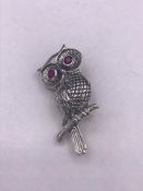 A silver owl brooch with ruby eyes