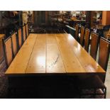 A Large Dining Table consisting of five large plank.s on a steel base with ten dining chairs.