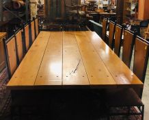 A Large Dining Table consisting of five large plank.s on a steel base with ten dining chairs.