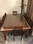 A large glass topped table made from an Antique Asian roof panel with eight chairs.