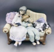 A Lladro figure of two children reading with their dog.