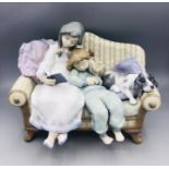 A Lladro figure of two children reading with their dog.