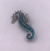 A silver and enamel sea horse shaped brooch with ruby eye