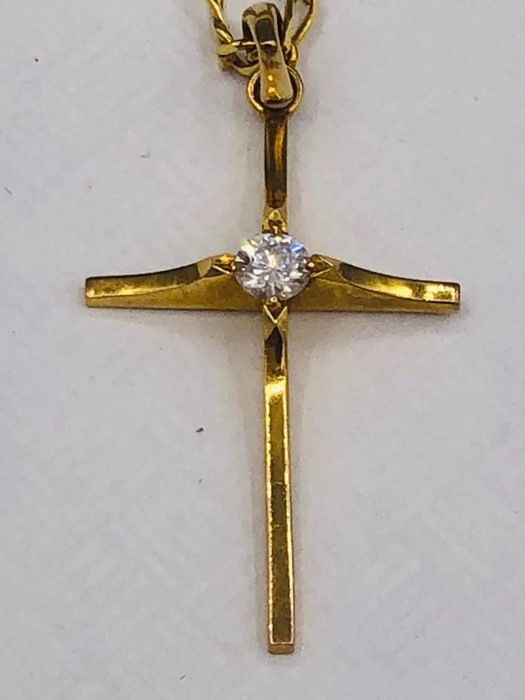 An Asian gold cross and chain with a central diamond set into the cross. The fastner on the chain